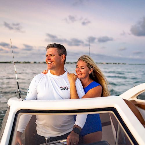 A man and woman are enjoying a boat ride with a scenic ocean backdrop during sunset, sharing a moment of joy and companionship.