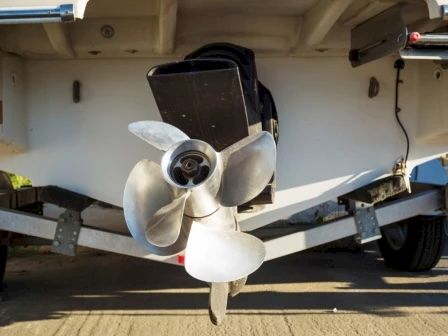 This image shows a close-up of a boat's propeller mounted on its motor, with the boat on a trailer.