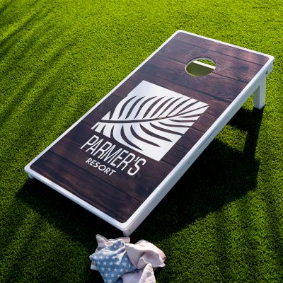 A cornhole board with a leaf design and the words 